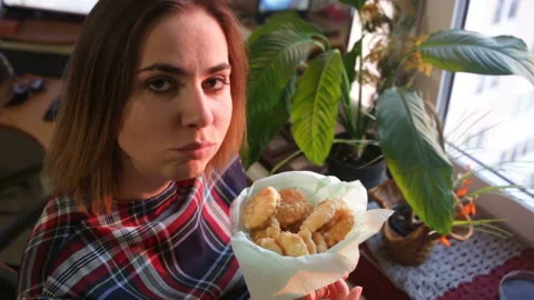 A woman chews a cookie looking at the camera close-up.  Top-down view, real time Stock Footage 87849087
