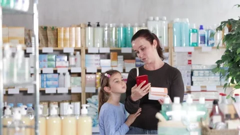 Woman with a child scans the barcode of a package of pills for children. Buyer Stock Footage 329540558