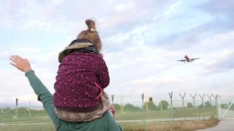 Woman with a child on shoulders joyfully greeted a plane landing near airport Stock Footage
