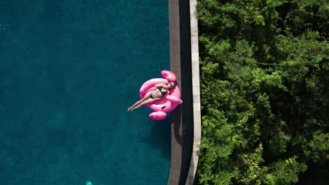 Woman chilling in infinity pool with pink inflatable flamingo. Sunbathing Video stock 246768384