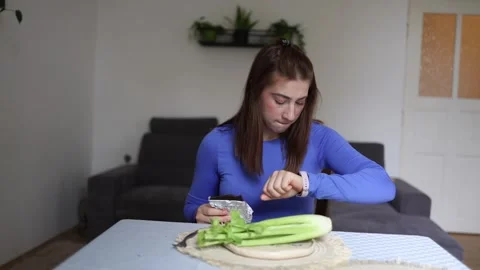 Woman chooses between healthy celery and chocolate at home Video stock 341237285