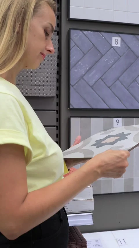 Woman chooses ceramic patterned tile with floral design in hardware store Stock Footage 316877496