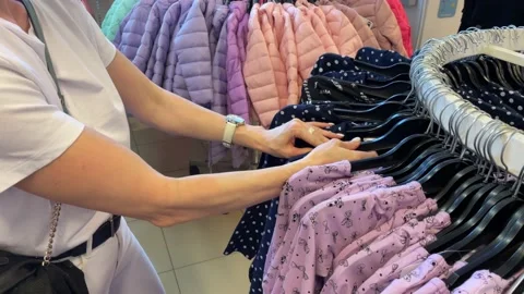 A woman chooses clothes on a rack in a store, buying clothes in a mall Stock Footage 238819879