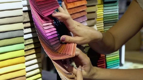 The woman chooses color of fabric on a rack. Close up of samples of fabrics. The Stock Footage