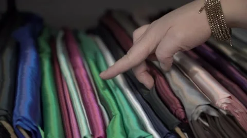 Woman chooses by hand colored fabrics in rolls on store shelves Video stock 169727892