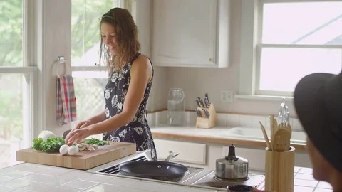 Woman chopping vegetables in a kitchen, while talking with her boyfriend Vídeos de archivo 74359452