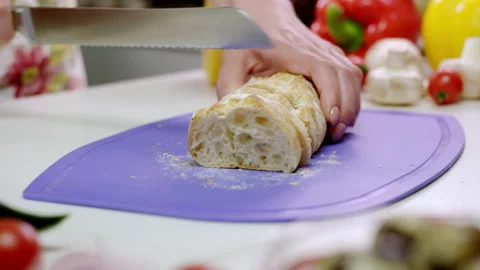 Woman chops bread on cutting board among ingredients Stock Footage 229847526