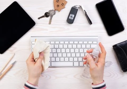 Woman cleaning a computer keyboard with an antiseptic spray Stock Photos