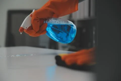 Woman cleaning table using rag and diffuser at home. Stock Photos