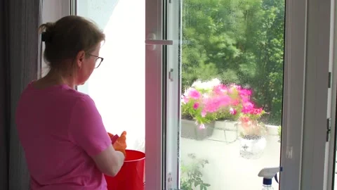 A woman cleans a window while wearing orange gloves Stock Footage 343430541