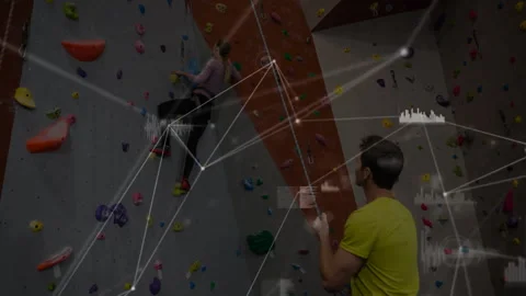 Woman climber testing holds to start ascent in gym, with data overlays tracing Stock Footage 312005166
