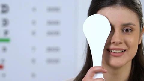 Woman closing one eye, checking vision in ophthalmology clinic, health care Stock Footage 110697274