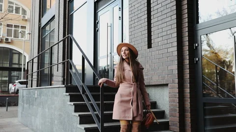 Woman in a coat and hat goes down the steps of the office building background Stock Footage 165737553