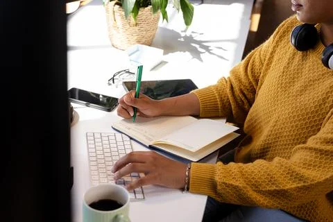 Woman coding at desk, writing notes in notebook, focused on work, at office Foto stock