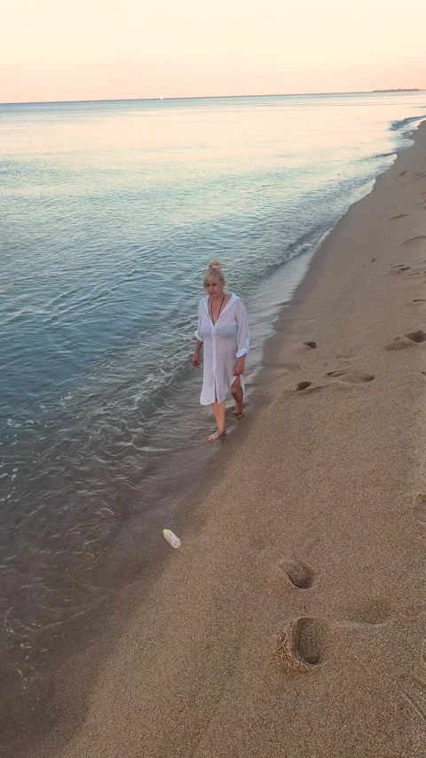 Woman collecting plastic waste while walking on beach , helping protect ocean Stock Footage 337411995
