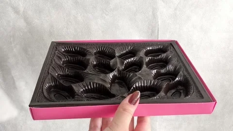 A woman collects packaging for sweets. Empty Chocolate Candy Box Vídeos de archivo 332409971