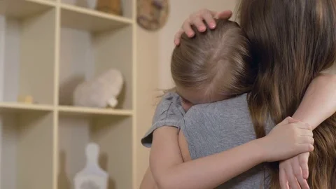 Woman comforting her upset or sick child carefully, mother hugging sad daughter Stock Footage