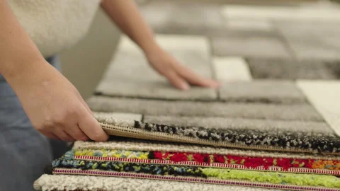 Woman comparing carpet texture and rug samples in home furnishing store Stock Footage 334580030