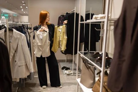 Woman comparing two vests while shopping in fashion store Stock Photos