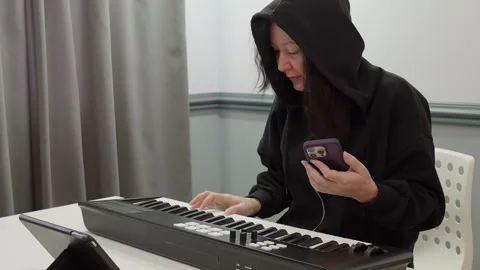 Woman composer using smartphone while playing synthesizer Video stock 293268731