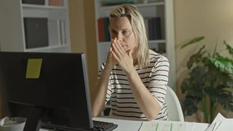 Woman at computer presses hands to face and leans toward screen in an offic.. Stock Footage 339254448