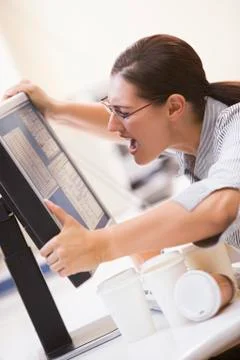 Woman in computer room grabbing her monitor and screaming Stock Photos