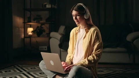 Woman concentrating on work, using laptop and headphones in a comfortable living Stock Footage 276552990