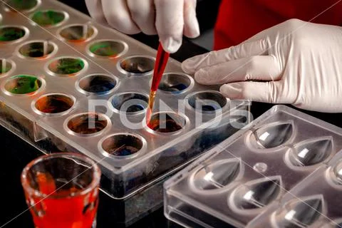 A woman confectioner with red uniform and white sterile gloves do a set of Stock Photos