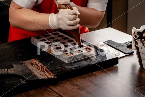 A woman confectioner with red uniform and white sterile gloves do a set of Stock Photos