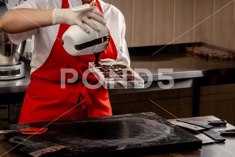 A woman confectioner with red uniform and white sterile gloves do a set of Stock Photos