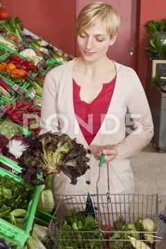 A woman contemplating a head of red leaf lettuce Stock Photos