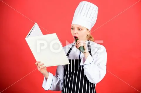 Woman in cook hat and apron eat cucumber. professional chef in kitchen. Cuisine Stock-Fotos