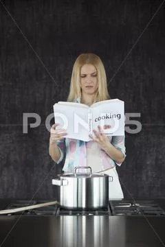 Woman cooking confused by cookery book. Stock Photos