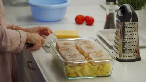 Woman cooking fish cod baked in oven with vegetables at home. Stock Footage 295283306