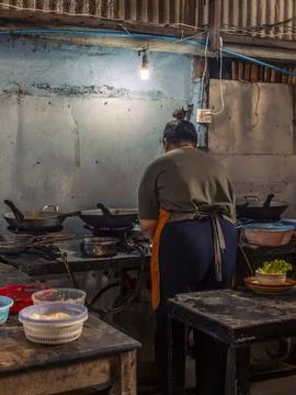 A woman cooking inside the basic kitchen of a restaurant in Kep in Cambodia Stock Photos