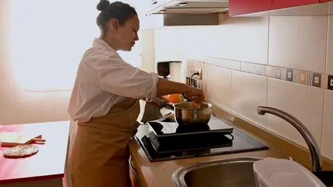 Woman Cooking in the Kitchen: Adding Ingredients to a Pot on the Stove Stock Footage 299656311