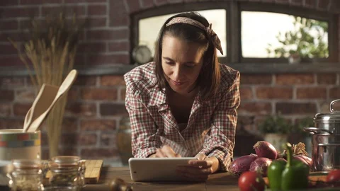 Woman cooking in the kitchen and using a digital tablet Stock Footage 128689716