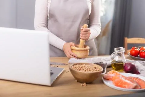 Woman cooking lunch using the computer to watch virtual culinary class Stockfoto's