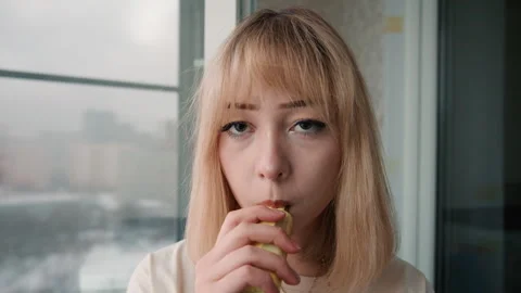 Woman cools bite. Portrait capturing woman blowing to ease hot sensation Stock Footage 337467876