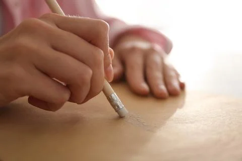 Woman correcting picture on paper with pencil eraser, closeup Stock Photos