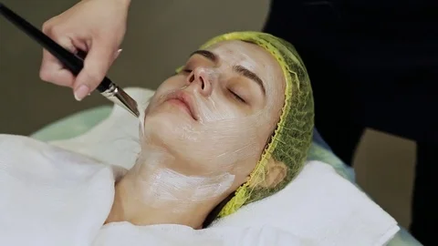 Woman cosmetologist to apply the cream-mask on the face. Cosmetic procedures Stock Footage