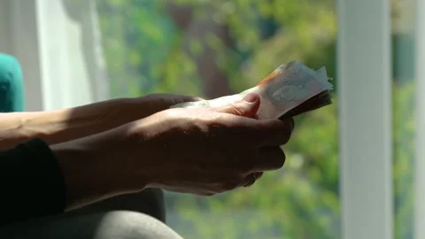 Woman counting pound notes with window background in natural light. Hands Stock Footage 312604543