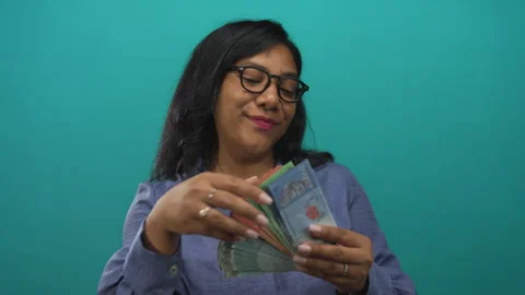 Woman counting ringgit banknotes in studio with teal background; wealth pro.. Stock Footage 314667158