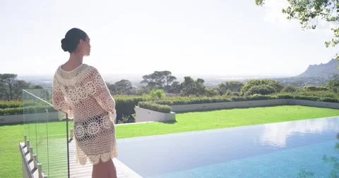 Woman in cover-up, leaning on railing by infinity pool, smiling as camera moving Stock Footage 336844853