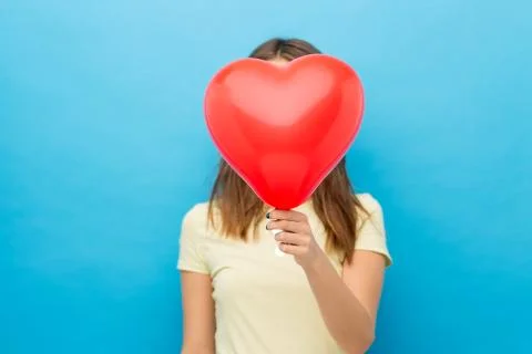 Woman covering face with heart-shaped balloon Stock Photos