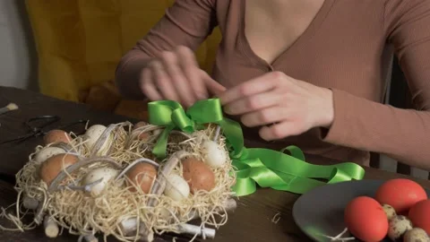 Woman creates Easter wreath with eggs at home at table Video stock 146232423