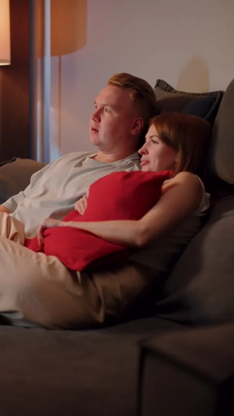 Woman cuddling with man on sofa while watching movie Video stock 323294440