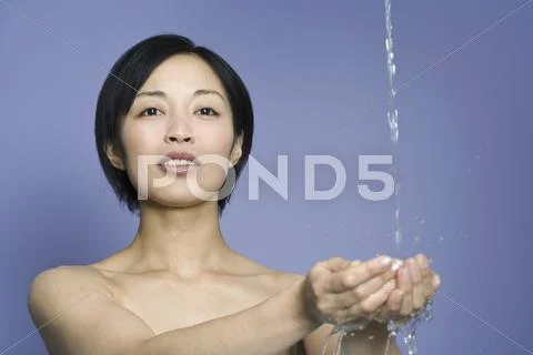 A woman cupping her hand under falling water Stock Photos