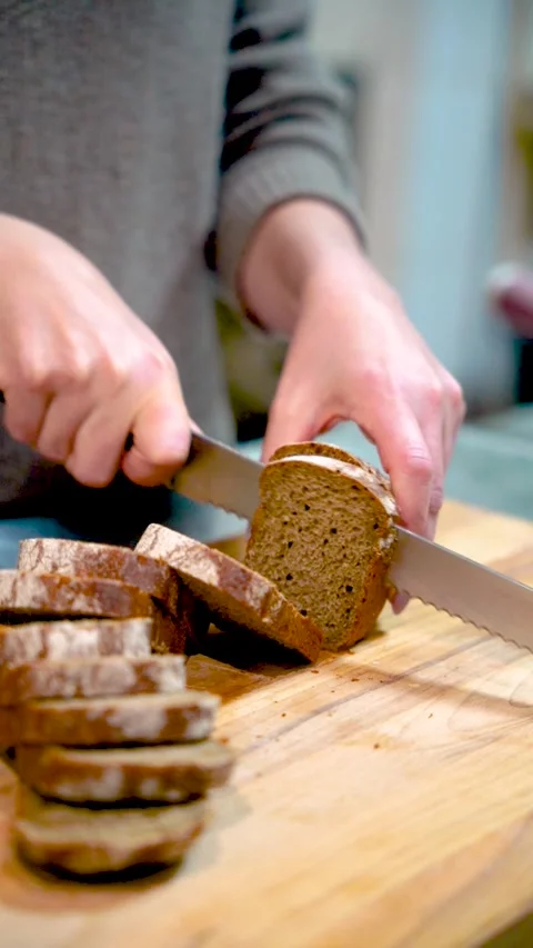 Woman cuts bread on kitchen cutting board Stock Footage 296451506