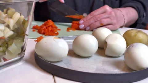 A woman cuts up cooked vegetables for making olivier salad 스톡 동영상 301881212